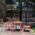 Modern outdoor seating area with red and wooden Nørrebro 3 Seater Public Backrest Benches and tables.