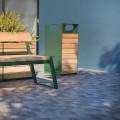 Nørrebro Street Litter Bin in green and wooden design next to a matching bench and a potted plant.