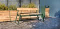 Outdoor bench and planter set with greenery in the background.