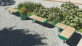 Banc Public Nordhavn 3 Places Sans Dossier en bois et métal vert, installé dans un jardin sur gravier, entouré de buissons.