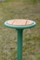 Tabouret d'extérieur Nordhavn en bois et métal vert sur fond de pelouse.