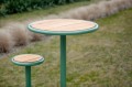 Table de bar d'extérieur Nordhavn de 70 cm avec plateau en bois et structure vert menthe, installée sur une pelouse.