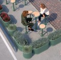 Jardinières d'extérieur Nordhavn | 130 l vertes entourant une terrasse avec des tables et des fauteuils.