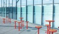 Red Nordhavn Bar Set: Table &amp; 4 Bar Stools outside a modern glass building.