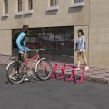 Support de vélo Ørestad rose installé devant un bâtiment moderne.