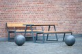 Amager 4 Seater Public Backrest Bench w/ Armrest placed beside a brick wall.