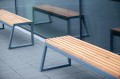 Banc Public Sans Dossier à 3 Places Amager en bois avec structure métallique, installé devant une vitre.