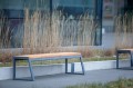 Öffentliche Bank Amager 4-Sitzer ohne Rückenlehne aus Holz und Metall, modern und stilvoll im Freien platziert.