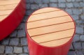 Tabouret d'extérieur Valby en bois et métal rouge sur fond de pavés.