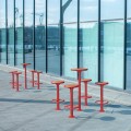 Table de bar extérieur Nordhavn de 110 cm avec tabourets rouges sur une terrasse moderne.