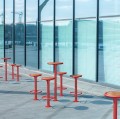 Nordhavn Bar Set: Table &amp; 4 Bar Stools in red with wooden seats outside modern glass building.