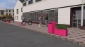 Rosa Ørestad Straßenabfallbehälter auf einer Bürgersteigkulisse.