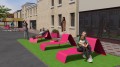 Ørestad Outdoor Planter | 150 l next to modern pink outdoor chairs on artificial grass area in front of a building