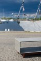 Concrete sideboard on a cobblestone surface with a marina in the background.
