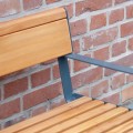 Holzbank Amager 1-Personen-Rückenlehnenbank mit Armlehne an Ziegelwand.