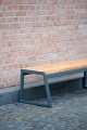Three Seater Public Backless Bench against a brick wall.
