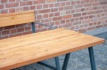 Table d'extérieur Amager 150 cm en bois avec structure en métal, placée sur une terrasse en pavés.