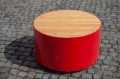 Valby Public Backless Bench | Round with red metal base and wooden top on cobblestone surface