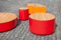 Valby Public Backless Bench | Round in bright red and orange on a cobblestone surface.