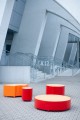 Rote und orange Valby Öffentliche Rückenfreie Bank in runder Form, auf einem Platz angeordnet.