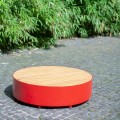 Valby Public Backless Bench | Round in a red finish on a stone pathway with green plants in the background.