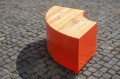 Banquette en bois et métal orange, design Valby Quart de Rond, sur pavé.