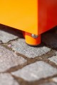 Pied du banc Banc Public Sans Dossier Valby | Quart de Rond en métal orange sur pavé.