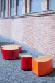 Viertelrunde Valby Öffentliche Rückenlose Bank in leuchtendem Orange und Rot vor Ziegelmauer.