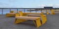 Table d'extérieur Nyboder en bois et métal jaune sur une terrasse avec vue sur l'eau.