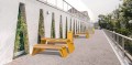 Mobilier urbain moderne avec tables et bancs en bois et métal jaune sur une esplanade.