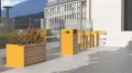 Support vélo Nyboder en métal jaune avec jardinière en bois et métal, installé en extérieur urbain.