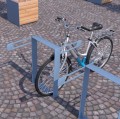 Moderner Nyboder Fahrradständer mit gesichertem Fahrrad in einem urbanen Umfeld.