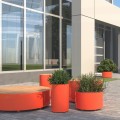 Jardinière Extérieure Tubulaire Valby orange devant un bâtiment moderne.