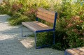Frederiksberg 3-Sitzer Öffentlichkeit Rückenlehnenbank aus Holz mit blauem Metallrahmen im Garten.