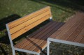 Banc public avec dossier Frederiksberg en bois et métal pour quatre personnes dans un parc.