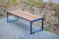 Banc public sans dossier à 3 places Frederiksberg, en bois et métal, installé sur un trottoir pavé.