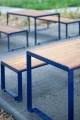 Frederiksberg 4-Sitzer öffentlicher rückennloser Bank aus Holz und Metall auf Gehweg.