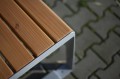 Frederiksberg Außenhocker aus Holz und Metall auf Pflastersteinen.