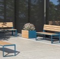 Frederiksberg Outdoor Planter 130 l with blooming flowers placed on modern patio with wooden benches.