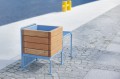 Østerbro Outdoor Hocker mit Pflanzkasten aus Holz und Metall auf Pflasterung.