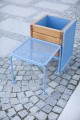 Blue metal Østerbro Outdoor Stool with wooden planter box on stone-paved ground.