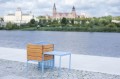 Tabouret d'extérieur Østerbro avec bac à fleurs en bois près d'un plan d'eau.