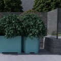 Jardinière d'extérieur Kødbyen de 70 litres avec plantes vertes luxuriantes en arrière-plan extérieur.