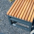 Moderner Hocker Hellerup Outdoor mit Holzsitz und Metallrahmen auf Kies.
