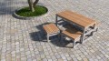 Moderner Hellerup Outdoor Hocker auf einem gepflasterten Platz neben einem Tisch und zwei Bänken.