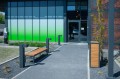 Banc urbain moderne et poubelle en bois Hellerup devant un bâtiment.