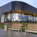Hellerup Street Litter Bin next to wooden benches outside a modern building.