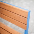 Wooden backrest of the Indre By 3 Seater Public Backrest Bench with blue metal frame.