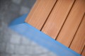 Close-up of Indre By 3 Seater Public Backless Bench with wooden slats and blue frame.