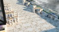 Tabouret d'extérieur Indre By sur une terrasse en pierre, entouré de tables et chaises.